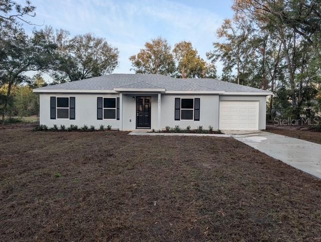 single story home featuring a garage, concrete driveway, and stucco siding