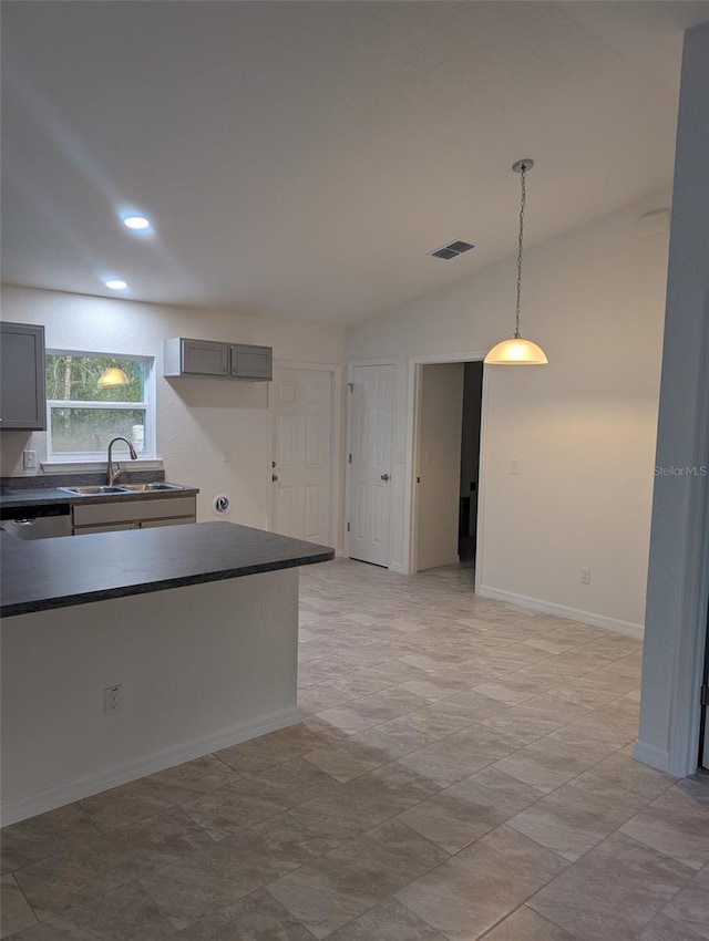 kitchen featuring gray cabinetry, a sink, visible vents, vaulted ceiling, and dark countertops