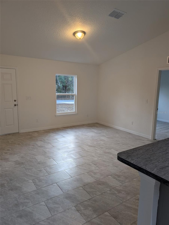 unfurnished room featuring visible vents, a textured ceiling, and baseboards