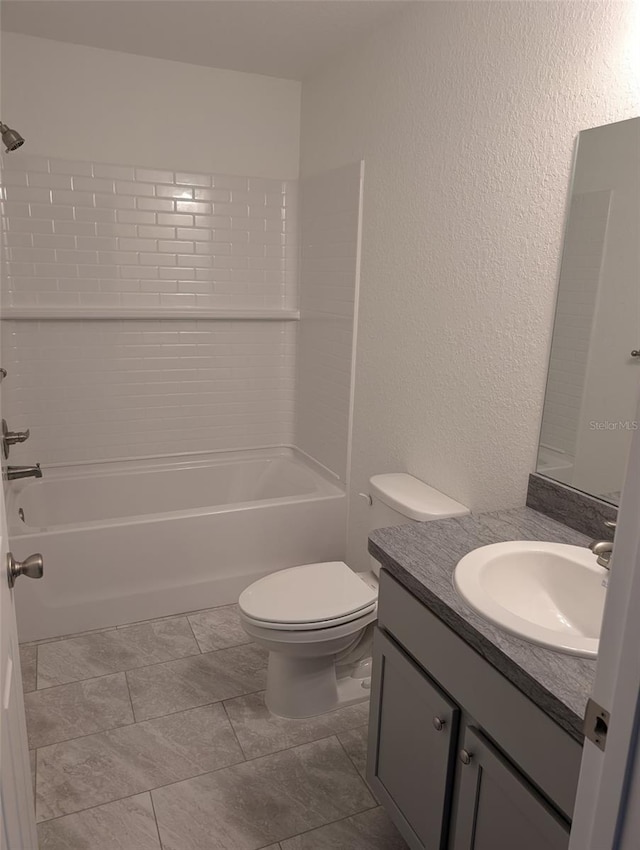 bathroom with toilet, a textured wall, vanity, and bathing tub / shower combination