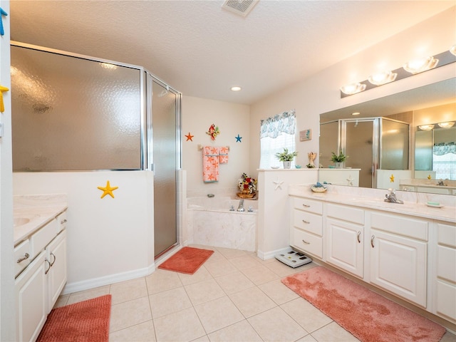 bathroom with visible vents, two vanities, a shower stall, tile patterned flooring, and a bath