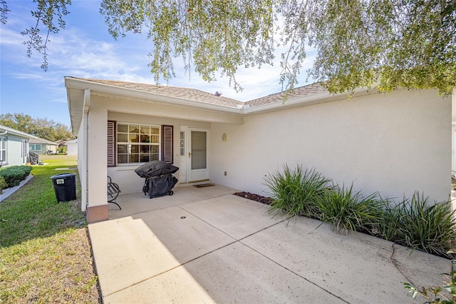 exterior space with a patio area, a lawn, and stucco siding