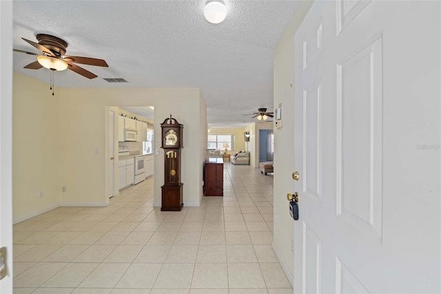 entrance foyer featuring a textured ceiling, visible vents, light tile patterned flooring, and a ceiling fan