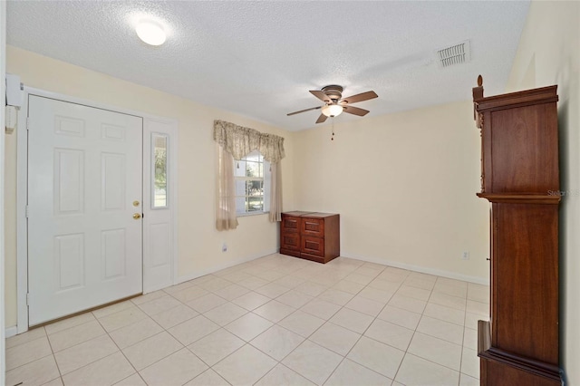 entrance foyer featuring ceiling fan, light tile patterned floors, a textured ceiling, visible vents, and baseboards