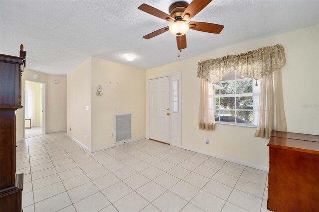 entrance foyer with a textured ceiling, light tile patterned flooring, visible vents, and baseboards