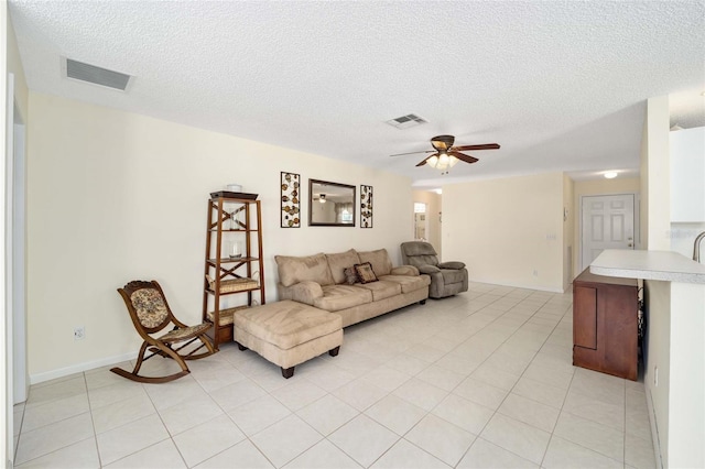 living room featuring a textured ceiling, light tile patterned floors, and visible vents