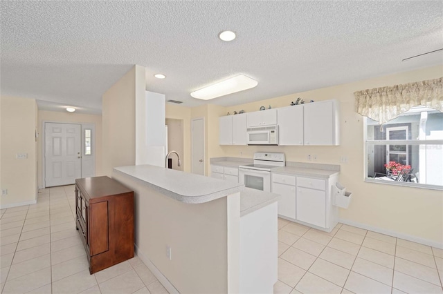 kitchen with light tile patterned floors, light countertops, white cabinets, white appliances, and a peninsula