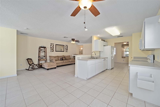 kitchen featuring white appliances, open floor plan, a sink, and light countertops