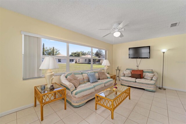 living room with visible vents, ceiling fan, a textured ceiling, baseboards, and tile patterned floors