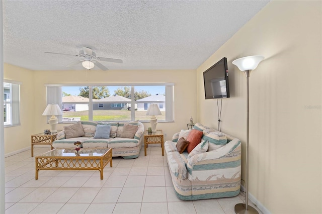 living room with light tile patterned floors, a textured ceiling, a ceiling fan, and baseboards