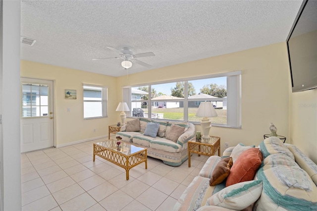living area featuring visible vents, light tile patterned flooring, ceiling fan, a textured ceiling, and baseboards