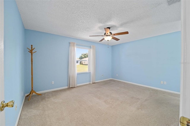 carpeted spare room featuring baseboards, a textured ceiling, visible vents, and a ceiling fan