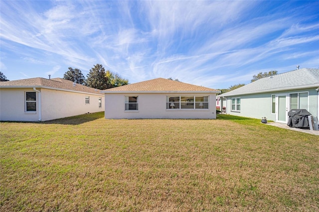 back of house featuring a yard and stucco siding