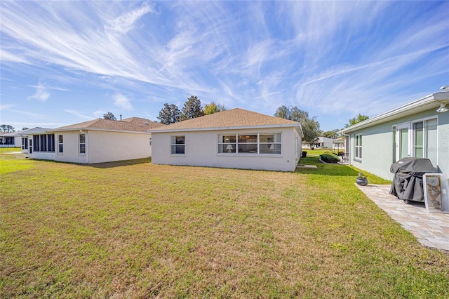 rear view of property featuring a yard and stucco siding
