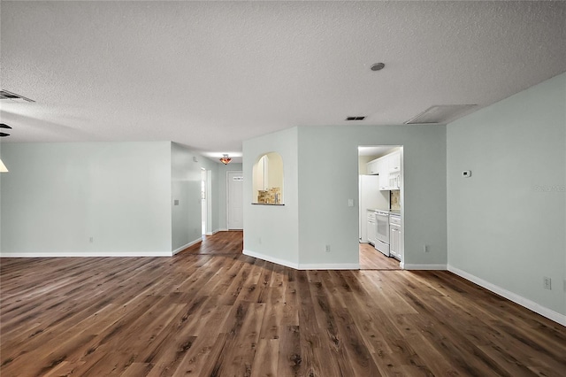 unfurnished living room featuring a textured ceiling, wood finished floors, visible vents, and baseboards