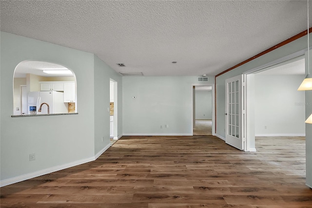 spare room featuring baseboards, a textured ceiling, visible vents, and wood finished floors