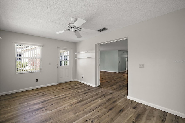 unfurnished room with dark wood-style floors, visible vents, a textured ceiling, and baseboards