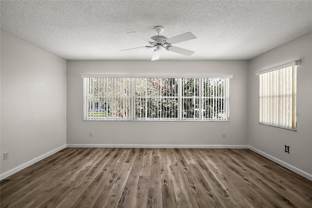 empty room with ceiling fan, a textured ceiling, baseboards, and wood finished floors