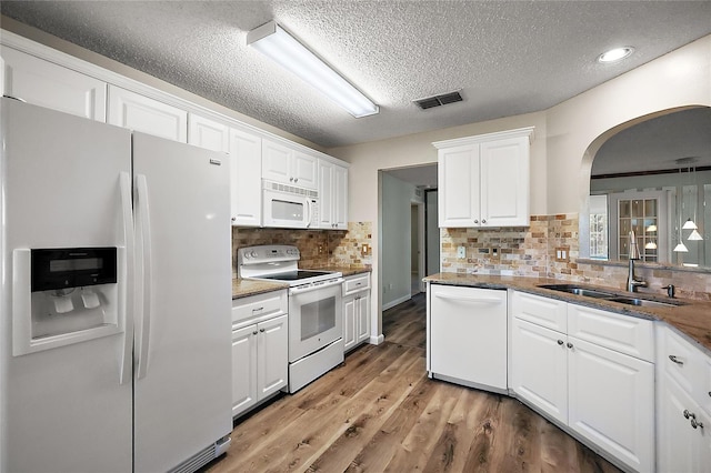 kitchen featuring white appliances, visible vents, light wood-style floors, white cabinetry, and a sink