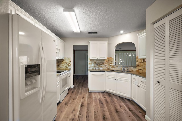 kitchen featuring white appliances, visible vents, dark wood-style flooring, white cabinetry, and a sink