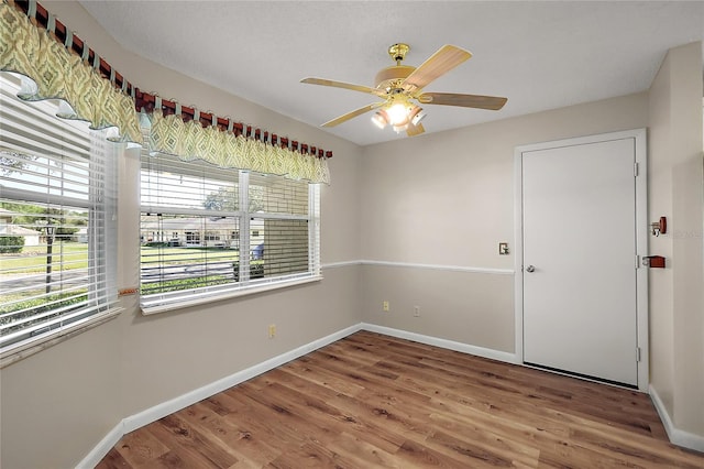 unfurnished room featuring ceiling fan, wood finished floors, and baseboards