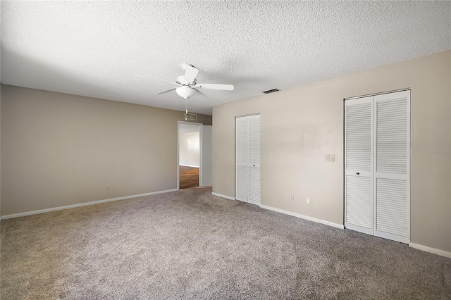 unfurnished bedroom featuring baseboards, visible vents, carpet, a textured ceiling, and multiple closets