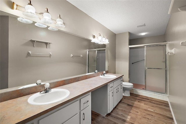 bathroom featuring visible vents, a sink, a textured ceiling, and a shower stall