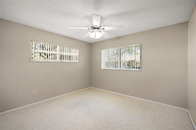 carpeted spare room with ceiling fan, baseboards, and a textured ceiling