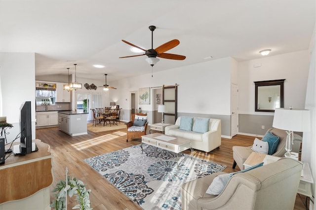 living room featuring light wood-style floors, lofted ceiling, ceiling fan, and baseboards