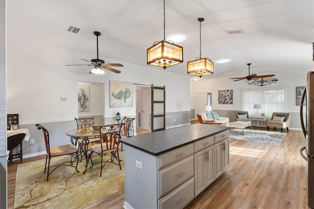 kitchen featuring lofted ceiling, a barn door, visible vents, open floor plan, and light wood-type flooring