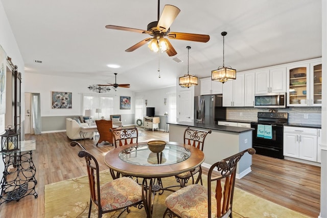 dining room featuring vaulted ceiling, light wood finished floors, a barn door, and visible vents