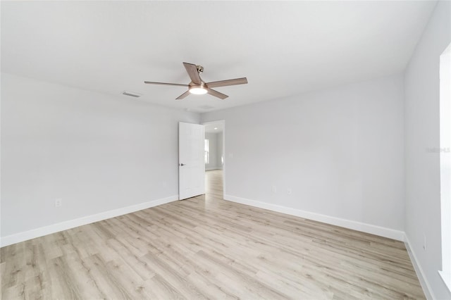 spare room with light wood-type flooring, ceiling fan, visible vents, and baseboards