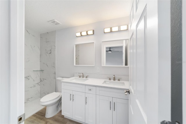 full bathroom featuring toilet, double vanity, a sink, and wood finished floors