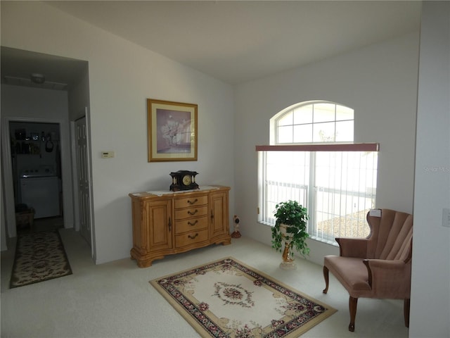 sitting room featuring vaulted ceiling, washer / clothes dryer, a wealth of natural light, and light colored carpet