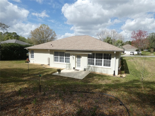 back of property with roof with shingles, a lawn, a patio area, and stucco siding