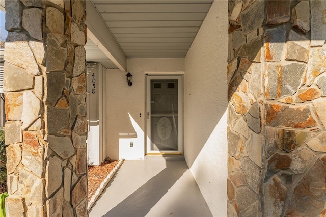 property entrance featuring stone siding and stucco siding