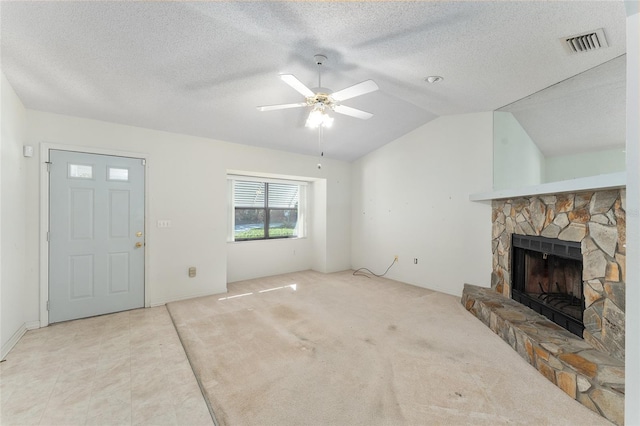 unfurnished living room featuring lofted ceiling, ceiling fan, carpet floors, a fireplace, and visible vents