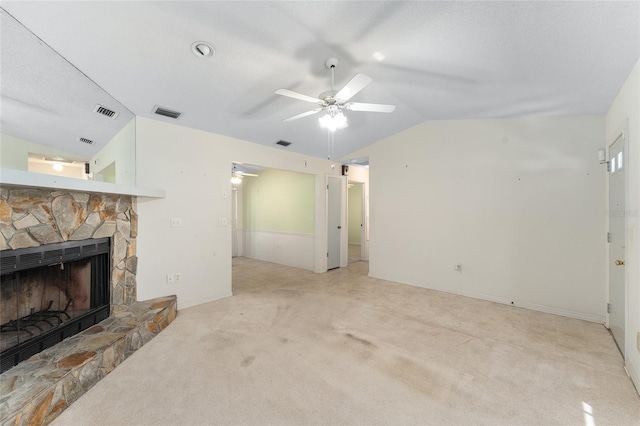 living room with lofted ceiling, visible vents, carpet flooring, ceiling fan, and a stone fireplace