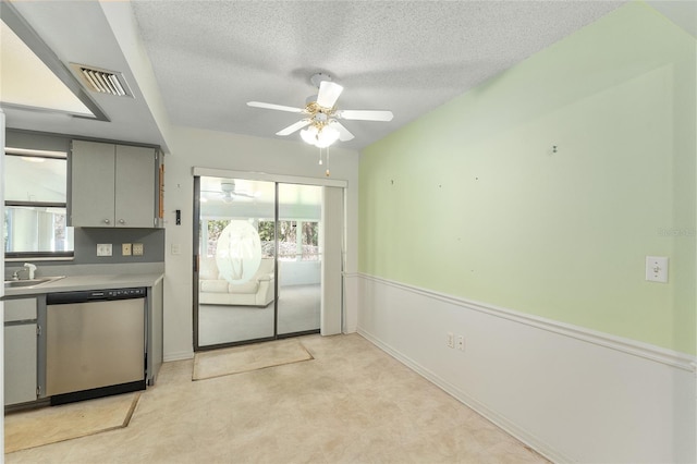 kitchen featuring visible vents, ceiling fan, gray cabinets, a textured ceiling, and stainless steel dishwasher