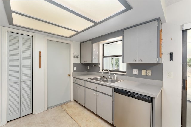 kitchen with gray cabinetry, light countertops, a sink, and stainless steel dishwasher