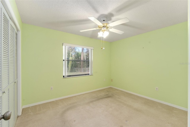 unfurnished bedroom with baseboards, ceiling fan, a textured ceiling, carpet flooring, and a closet