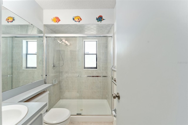 bathroom featuring toilet, a textured ceiling, a shower stall, and vanity