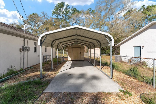 view of vehicle parking featuring a shed, fence, and a detached carport