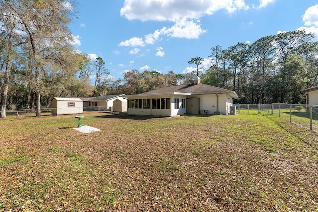 rear view of house with a yard, a fenced backyard, and a sunroom