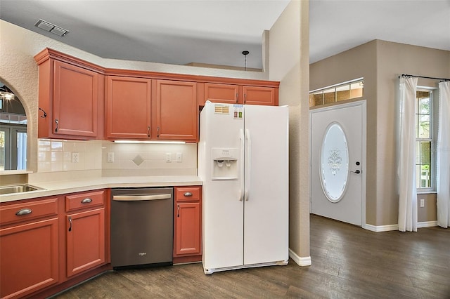 kitchen with white refrigerator with ice dispenser, visible vents, stainless steel dishwasher, backsplash, and dark wood finished floors