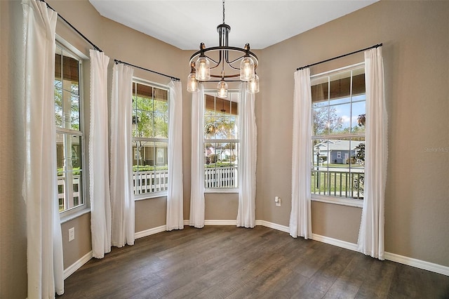 doorway to outside with dark wood-style flooring, a notable chandelier, and baseboards