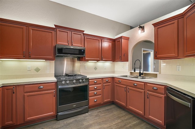 kitchen featuring arched walkways, dark wood finished floors, a sink, gas range oven, and stainless steel dishwasher