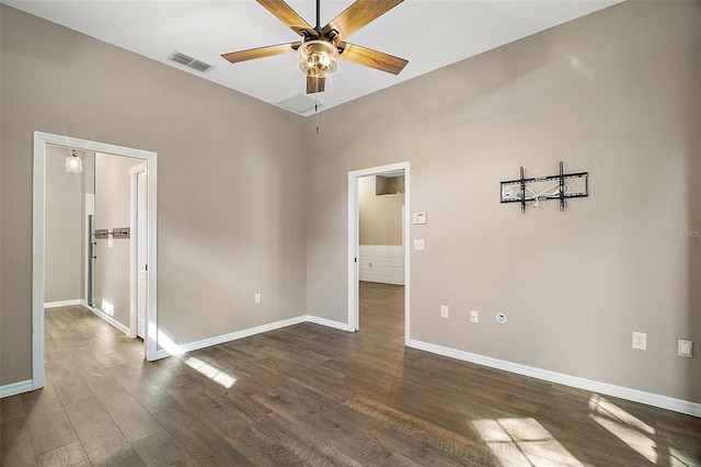 empty room featuring baseboards, dark wood-type flooring, visible vents, and a ceiling fan