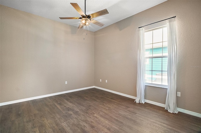 empty room featuring a ceiling fan, baseboards, and dark wood-type flooring