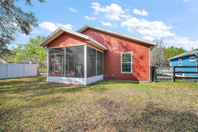 back of house featuring a sunroom, a fenced backyard, and a lawn